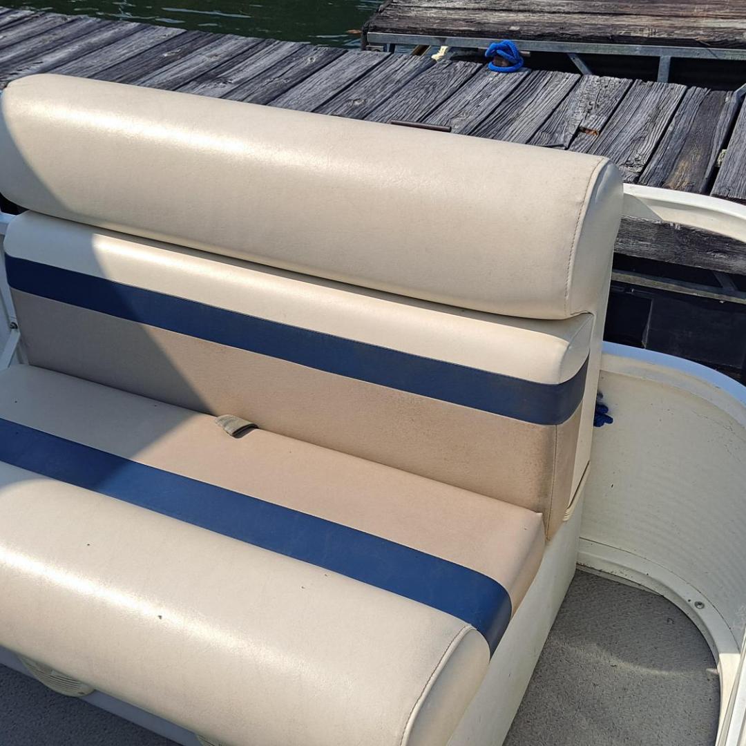 Boat bench seat with blue stripes beside wooden dock in sunlight.