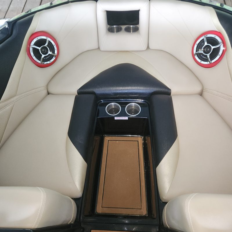 Boat seating area with beige cushions and red speakers.