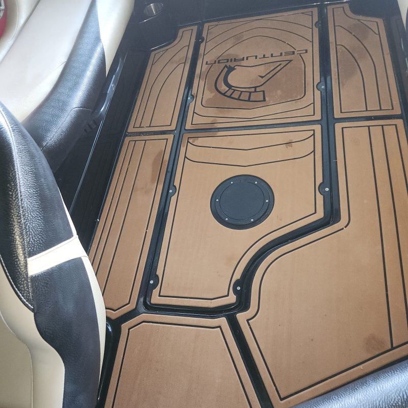 Boat deck with brown flooring and black lines, between beige and black seats.