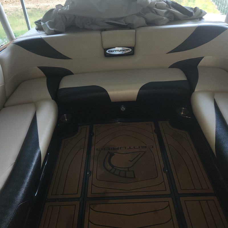 Interior view of a boat with cushioned seats and a wooden floor
