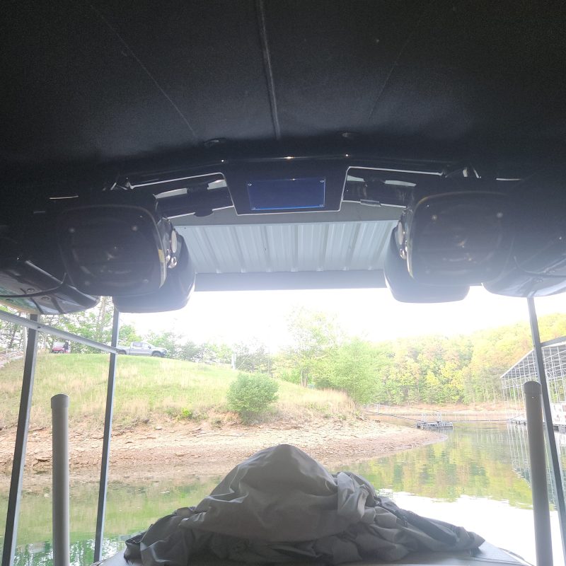 View from inside a boat with covered seats overlooking a dock.