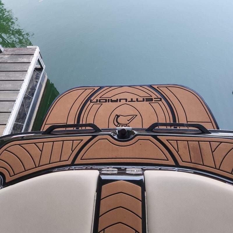 Top view of a boat deck with 'Centurion' logo near water and dock.