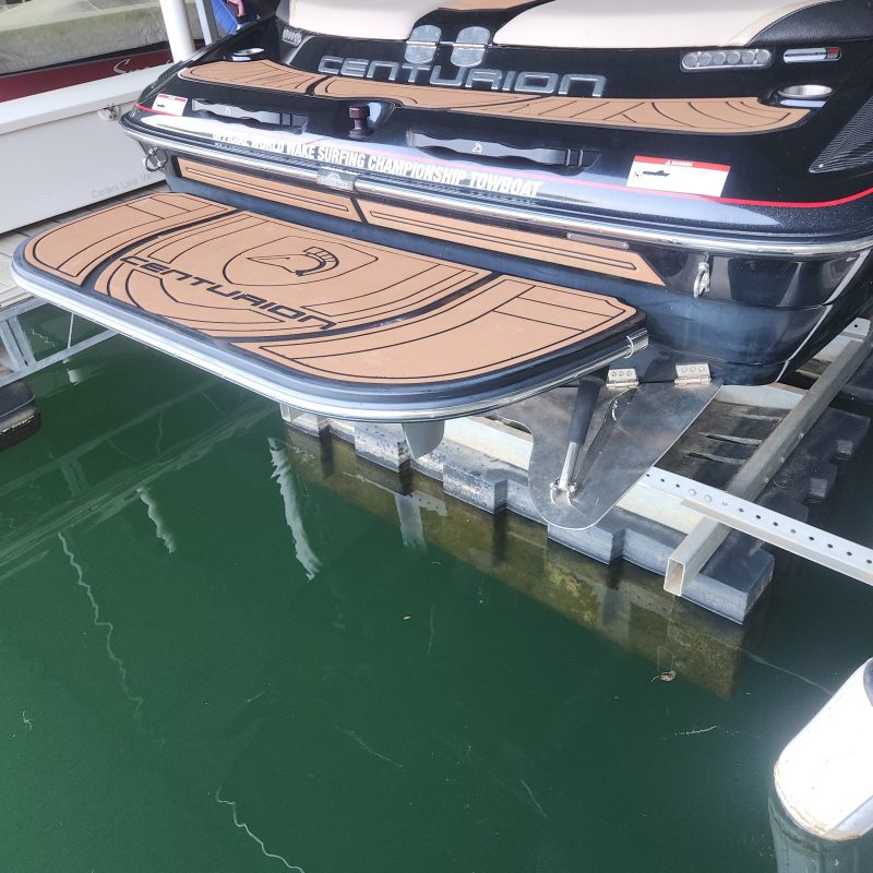 A boat with a brown deck is docked on calm green water.