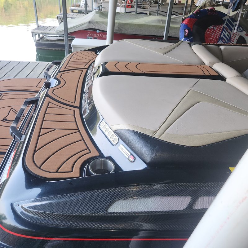 Parked jet ski with brown seating on dock under a canopy.