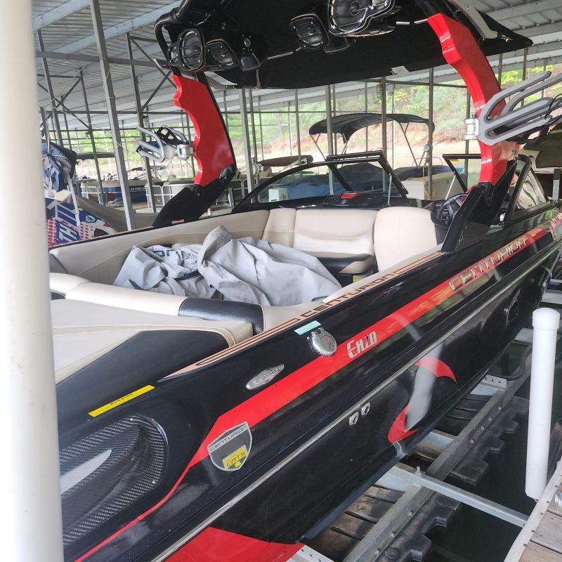 Sport boat stored under a metal roof in a dock area.