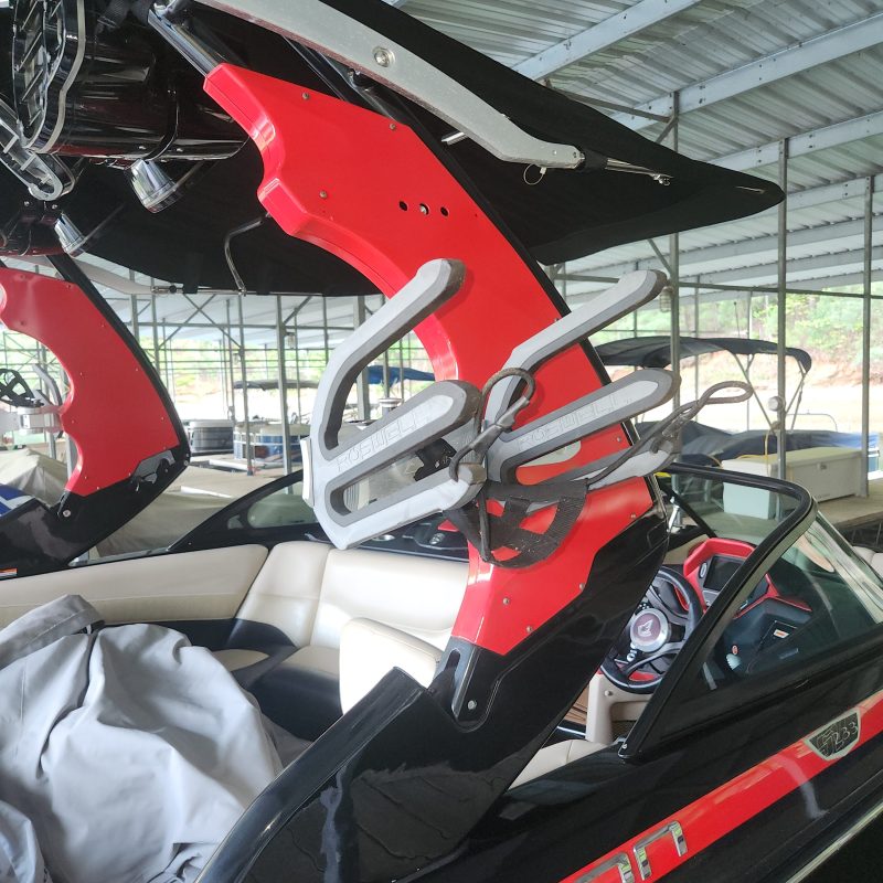 Red and black wakeboard tower attached to a boat inside a metal structure.