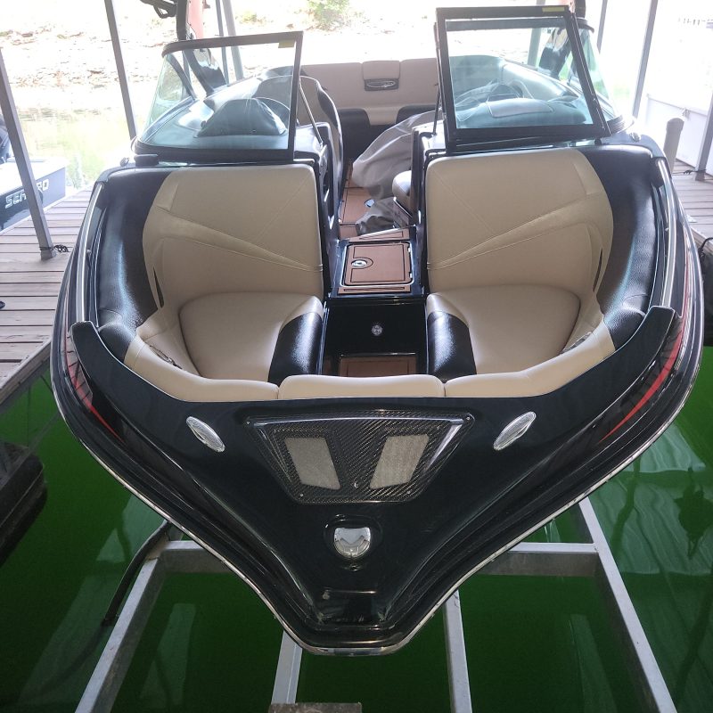 Front view of a luxury speedboat docked, featuring beige seats and a sleek black outer design.