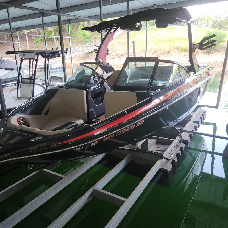 Boat stored in a covered dock with green exterior and black railing.
