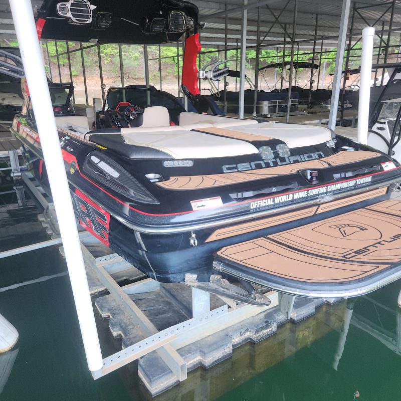 Boat on lift in covered dock, showing the stern and seating area.