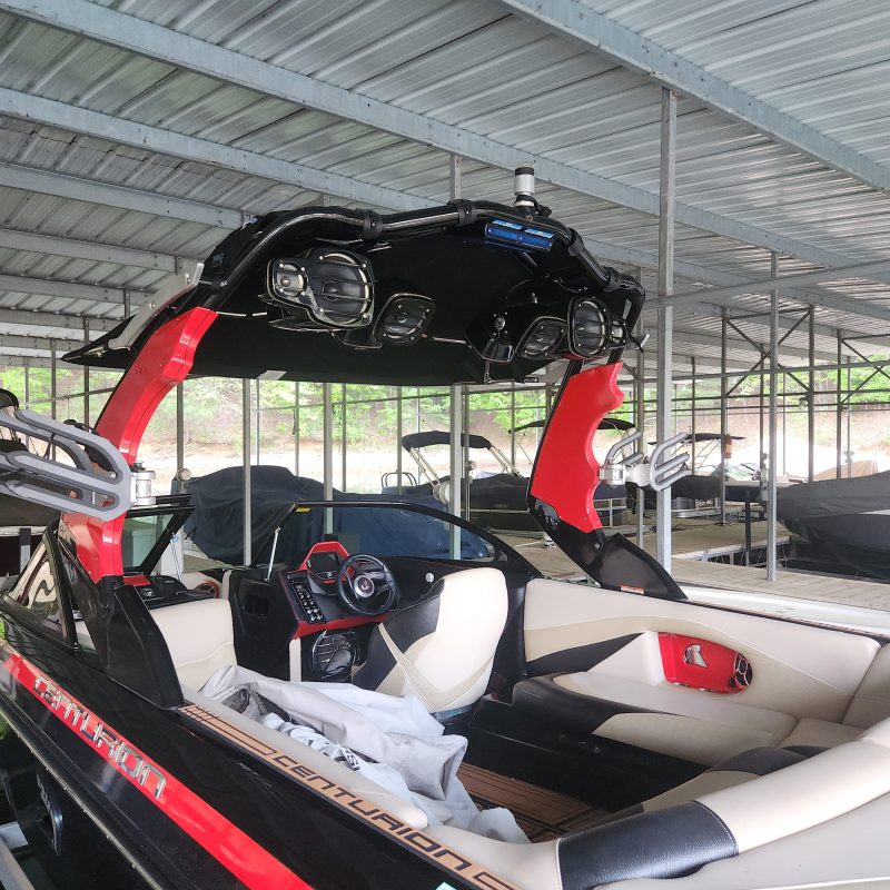 Boat with red and black detail under a metal roof.
