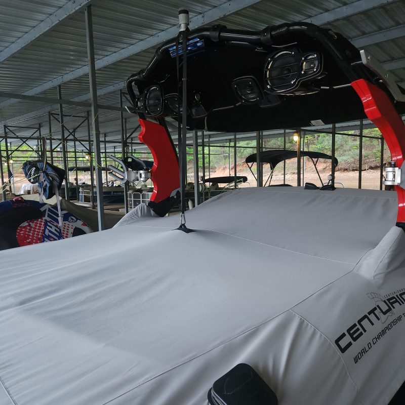 Covered boat stored in a metal-roofed shelter.