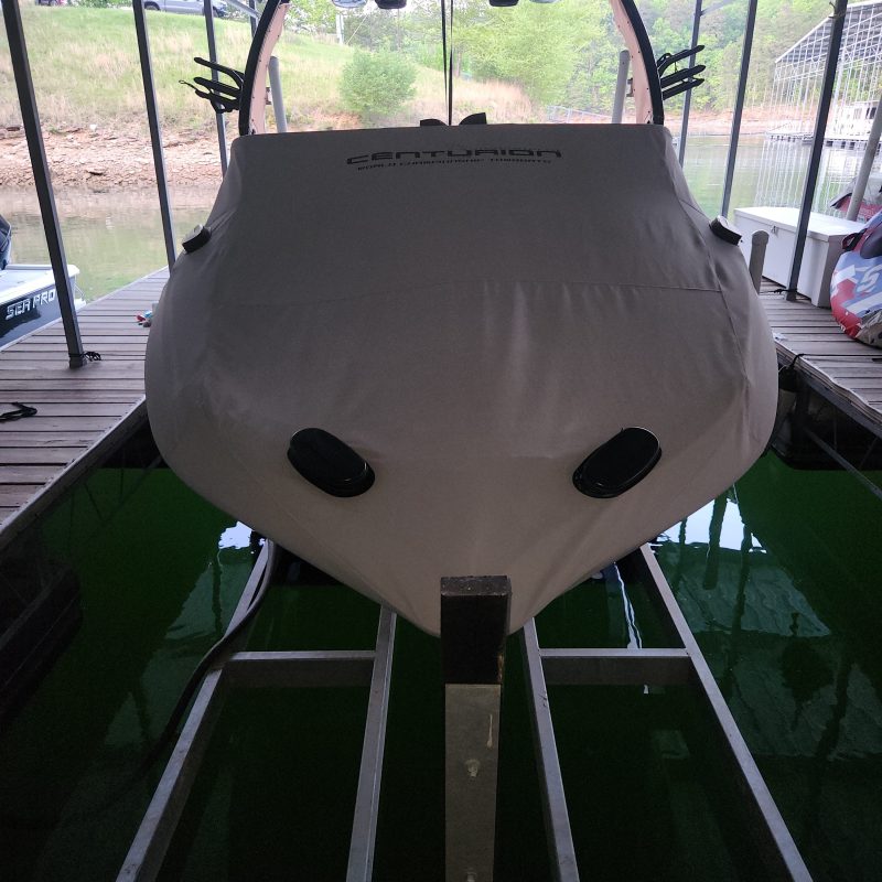 A boat with a cover inside a dock, partially visible on a sunny day.