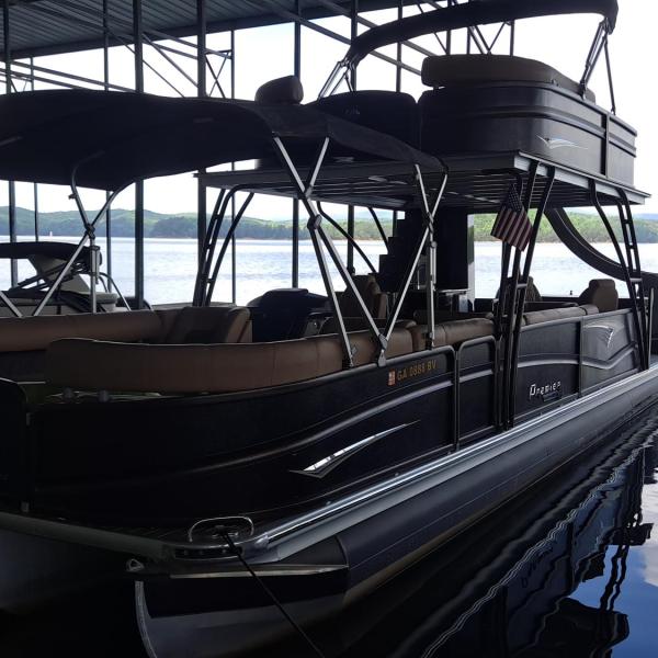 Large pontoon boat docked in a marina with a lake view.
