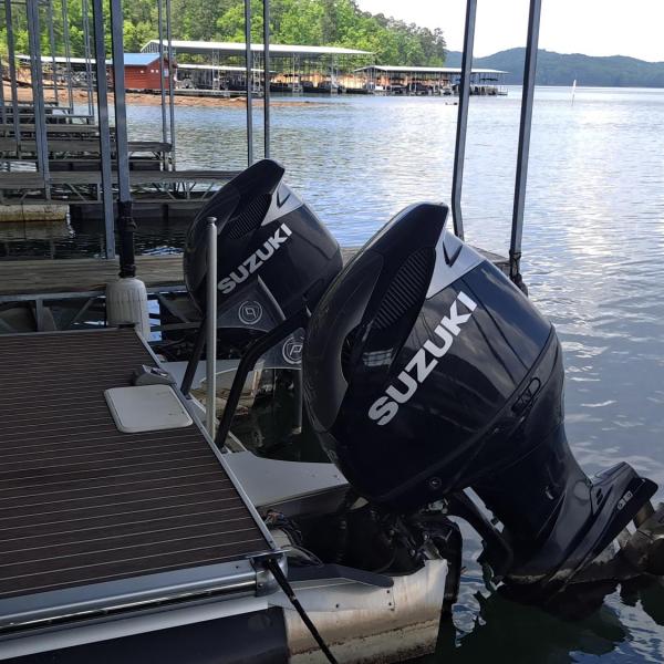 Boat engines labeled Suzuki on a dock by a lake.