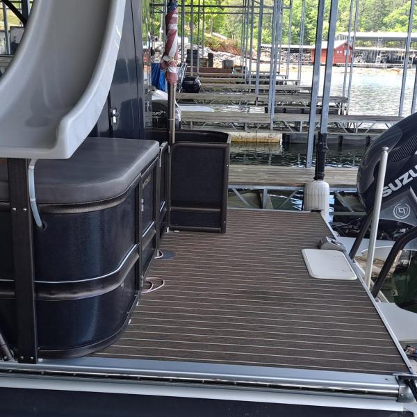 Boat with Suzuki engines at dock, slide on top, water and other boats in background.