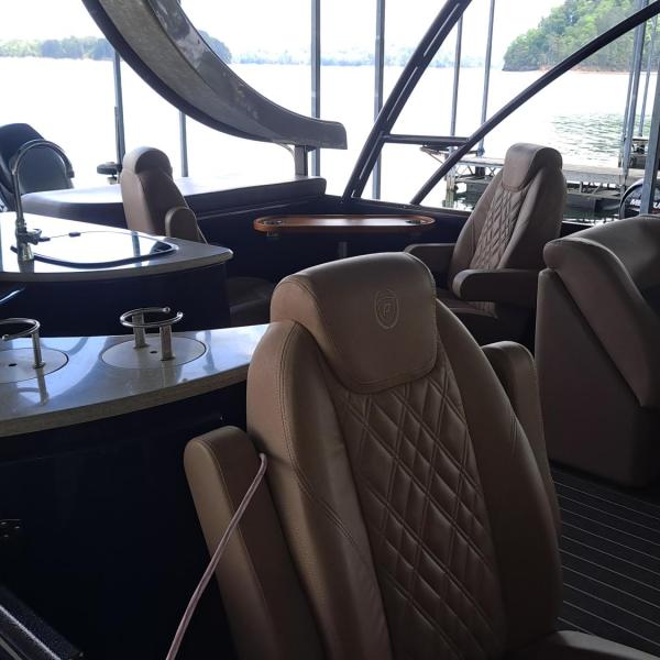 Luxury boat interior with leather seating and helm, overlooking a lake.