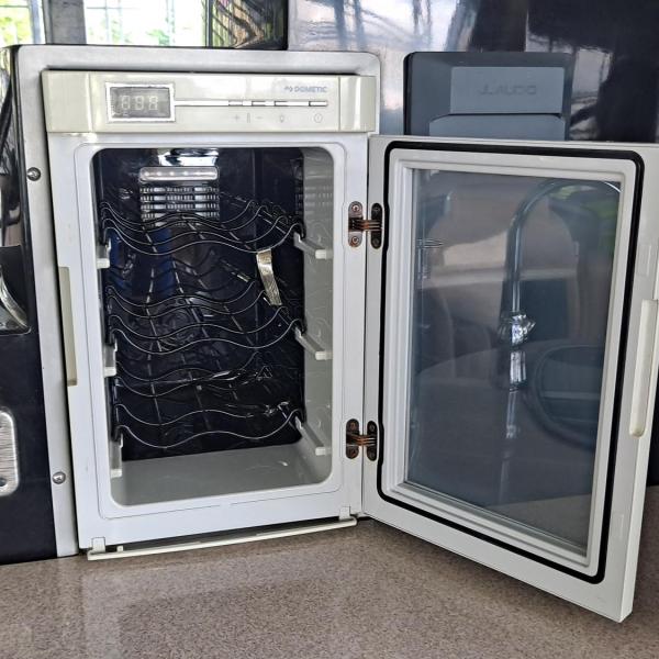 Open mini fridge with empty wire racks on a countertop.