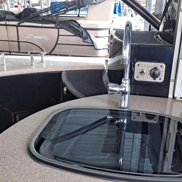 Boat interior with sink and cabinet, docked pontoon boat in background.