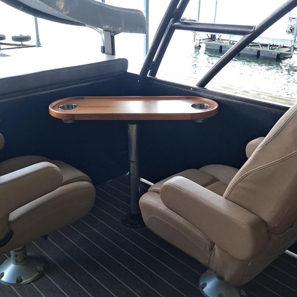 Two brown boat seats facing a small wooden table on a boat.