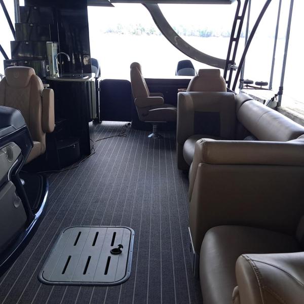 Interior of a boat with tan seating and a striped floor.