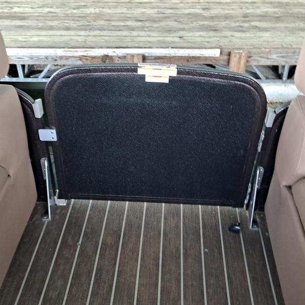 Interior of a boat with two brown seats and a closed gate.