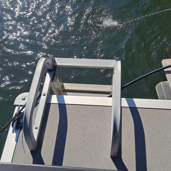 Boat ladder on a dock with water and boat motor visible.
