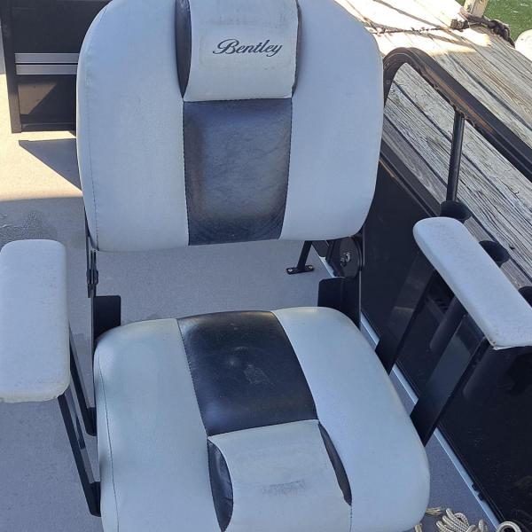 White and black cushioned boat seat with armrests on a deck.