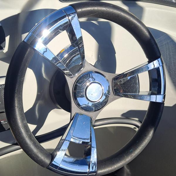 Chrome and black steering wheel in a boat cockpit.