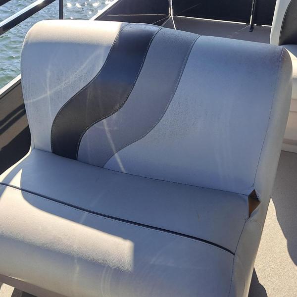 Boat seating with gray cushions and black railing, lake water in the background.