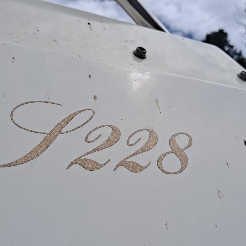 Close-up of a white surface with 'S228' in elegant script.